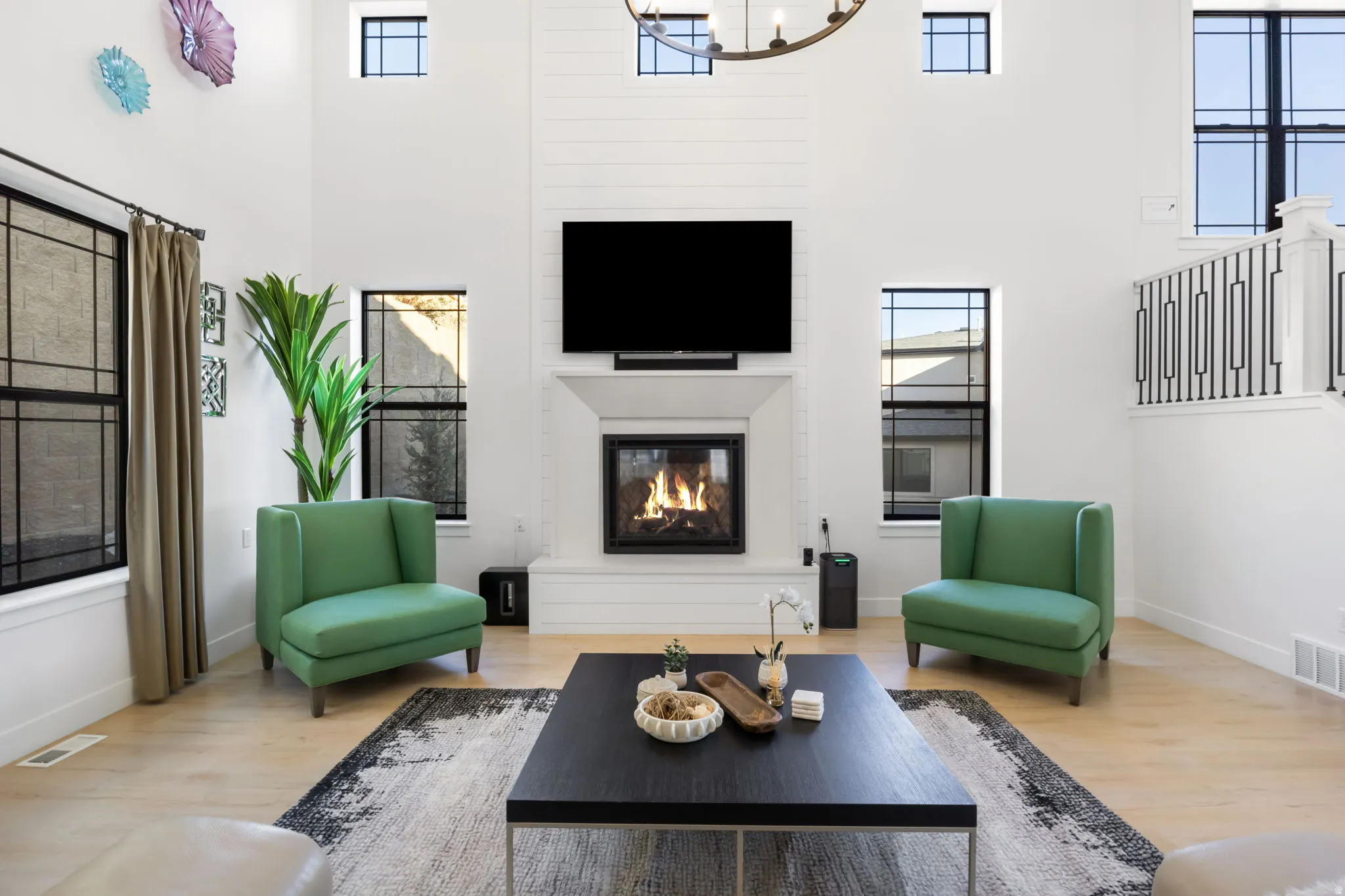 Living room featuring a large fireplace, wood finished floors, a high ceiling, and healthy amount of natural light