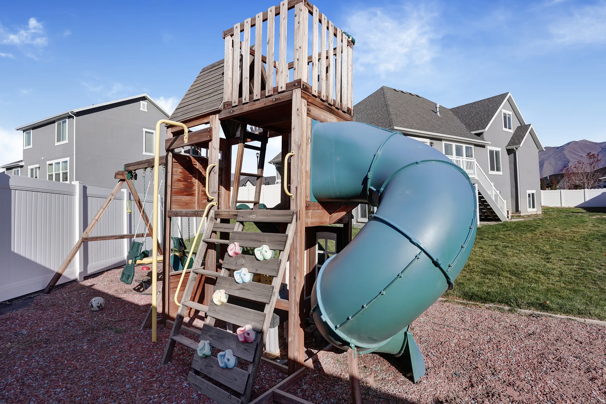 View of playground featuring a fenced backyard, a mountain view, and stairs