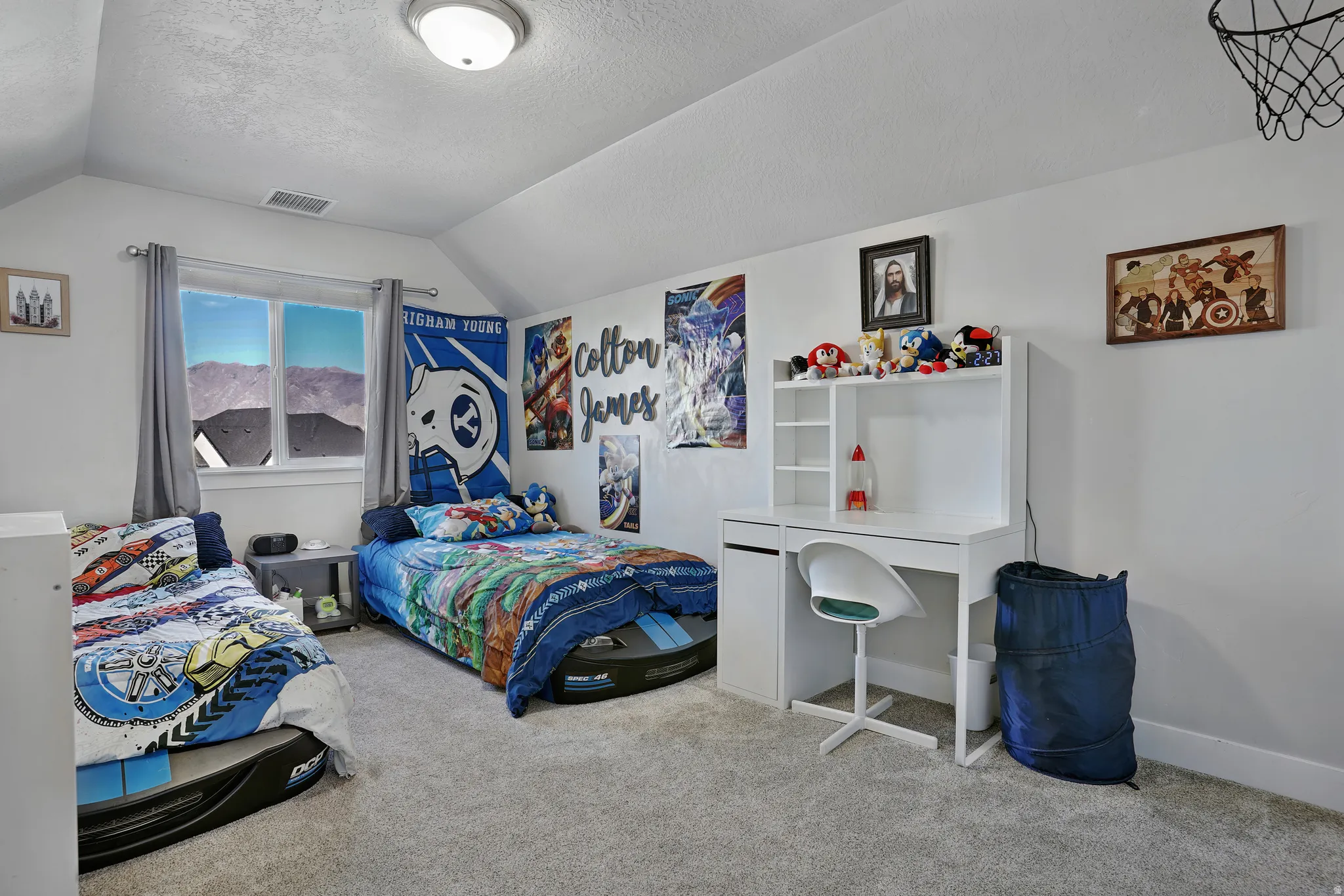 Bedroom with lofted ceiling, light colored carpet, and a textured ceiling