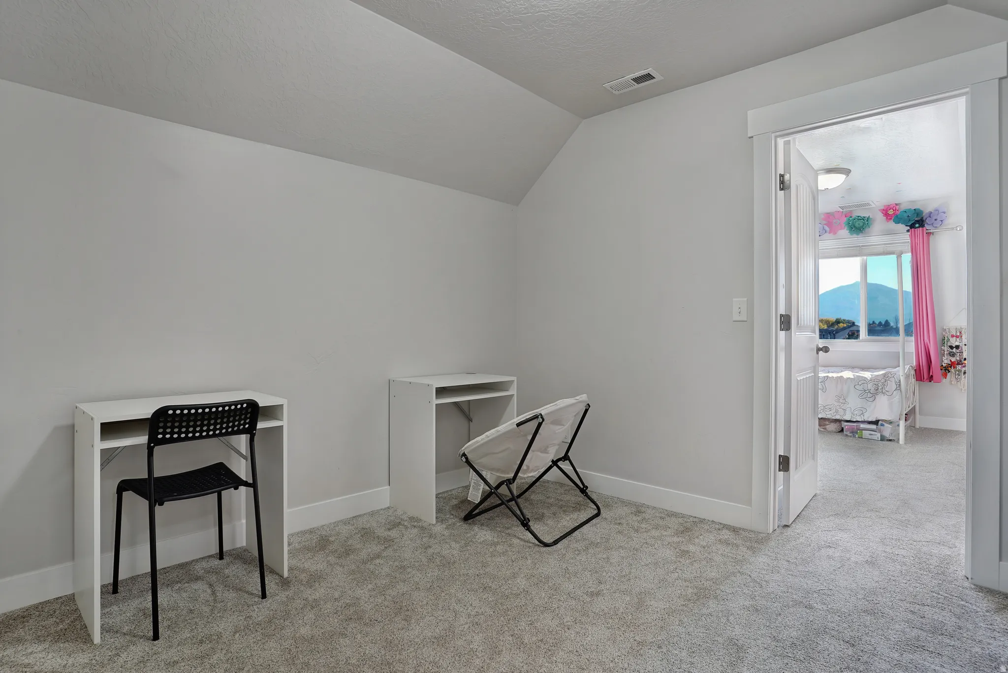 Home office featuring vaulted ceiling, a textured ceiling, and light carpet
