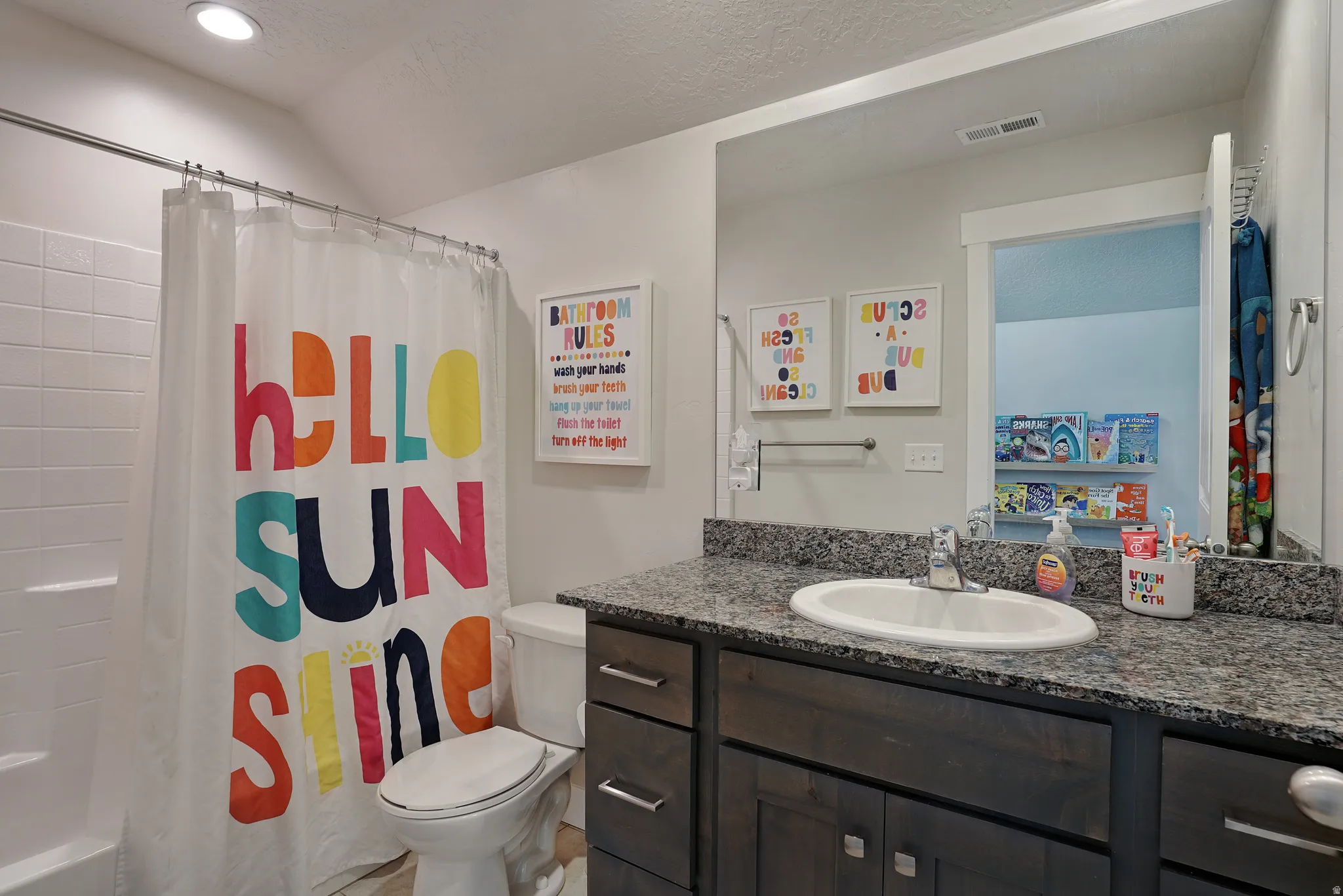 Bathroom featuring a textured ceiling, vanity, shower / bath combo with shower curtain, and vaulted ceiling