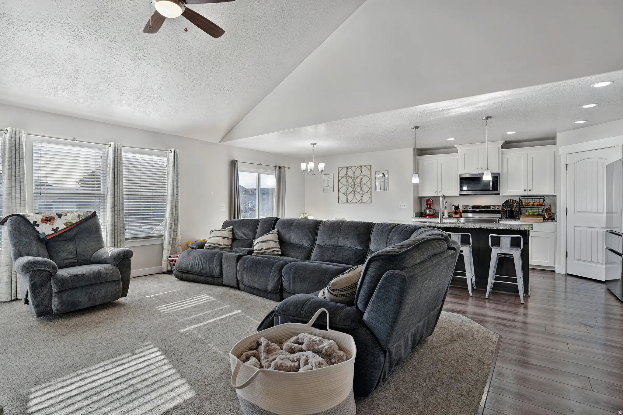 Living area featuring a textured ceiling, ceiling fan, and high vaulted ceiling