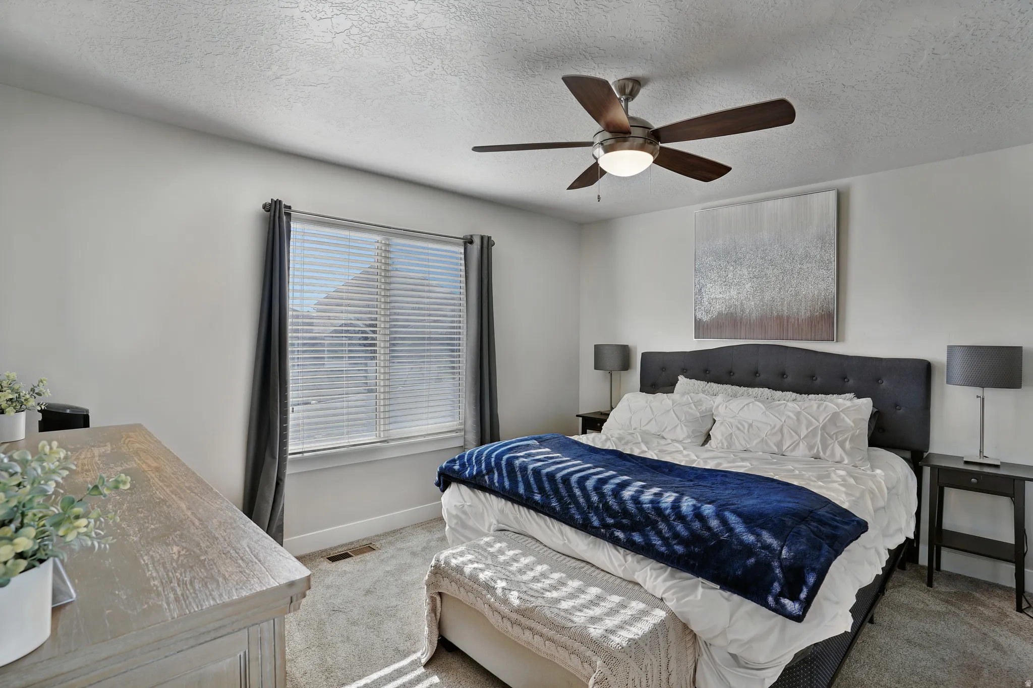 Carpeted bedroom featuring a textured ceiling and a ceiling fan