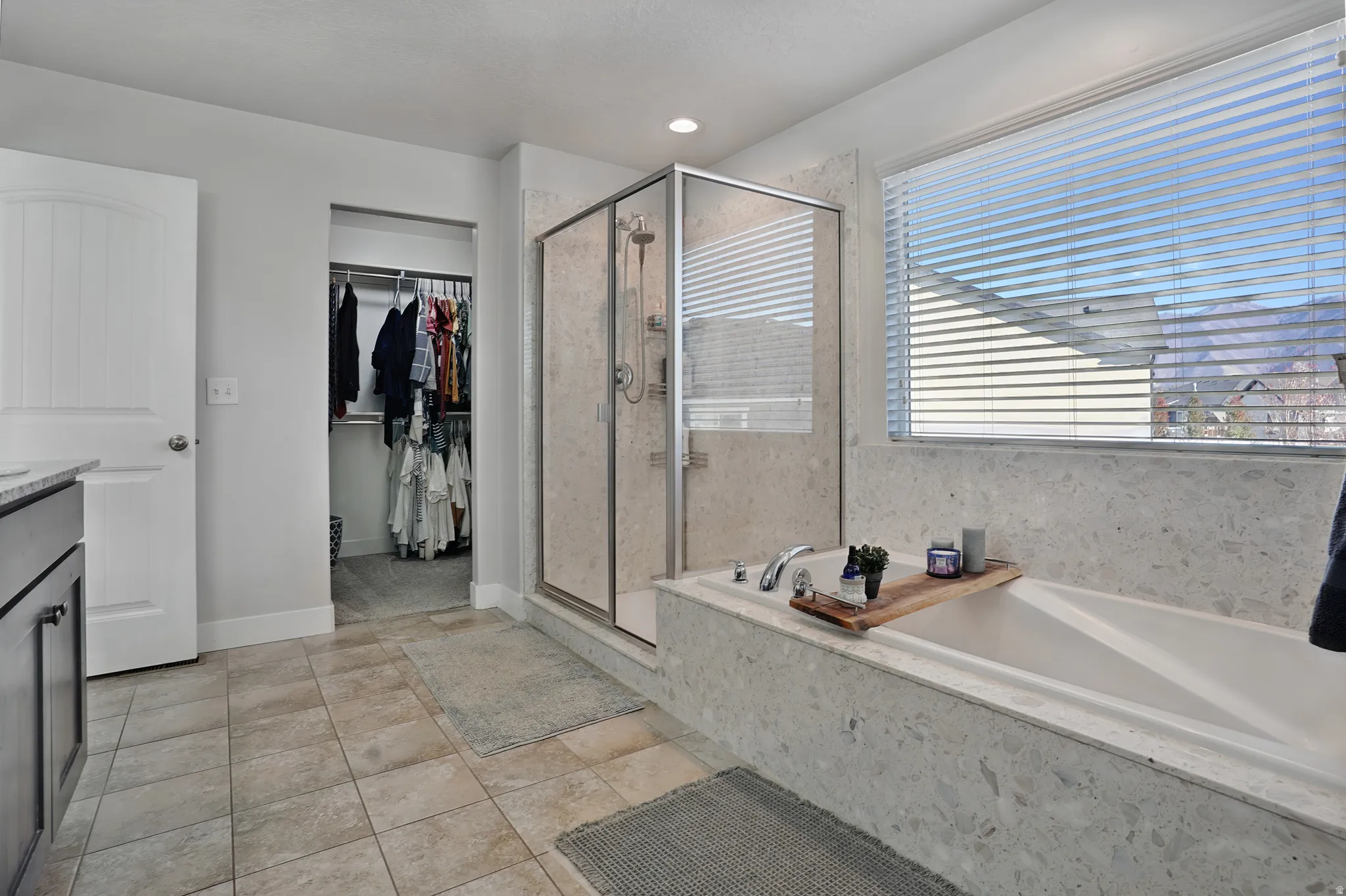 Full bathroom featuring vanity, a stall shower, a bath, a spacious closet, and light tile patterned floors