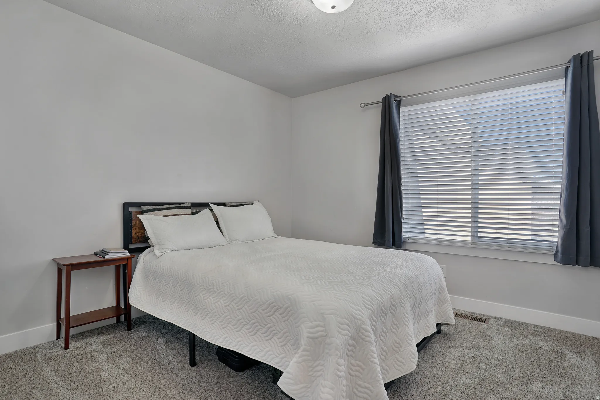 Carpeted bedroom featuring baseboards and a textured ceiling