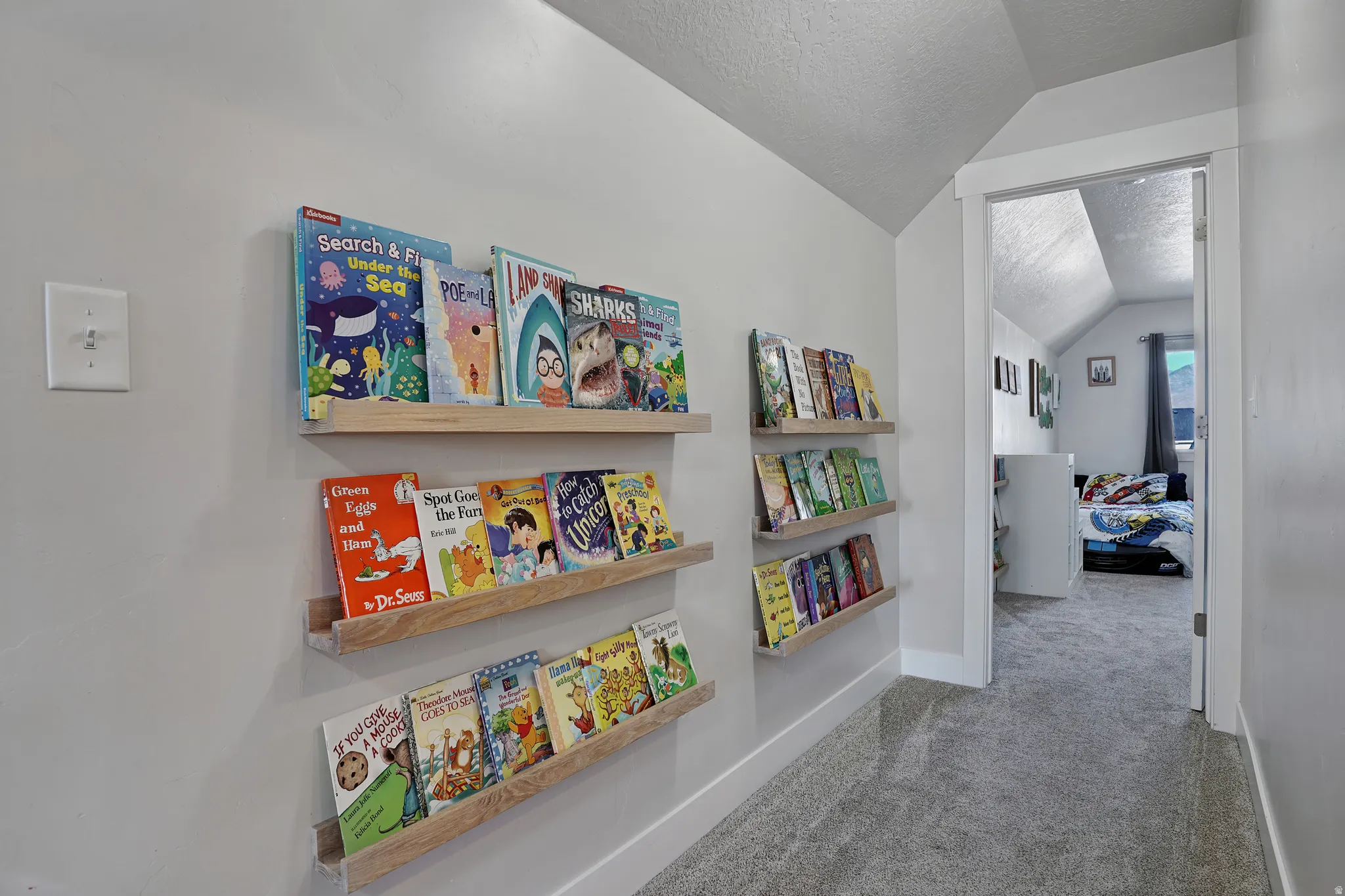 Hall featuring a textured ceiling, lofted ceiling, and carpet floors