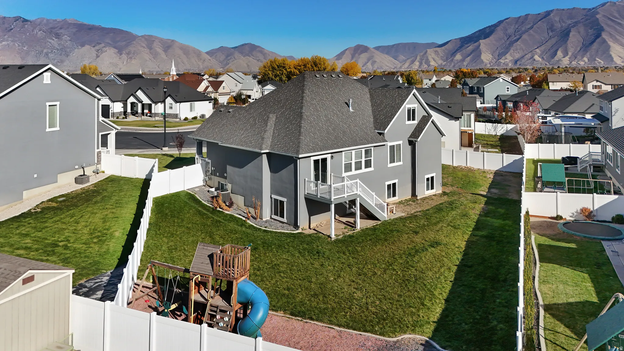 Back of property featuring a fenced backyard, a shingled roof, stucco siding, and a residential view