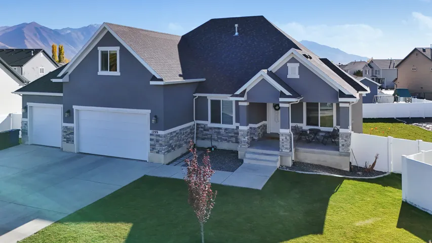 View of front of property with a mountain view, driveway, stucco siding, and stone siding