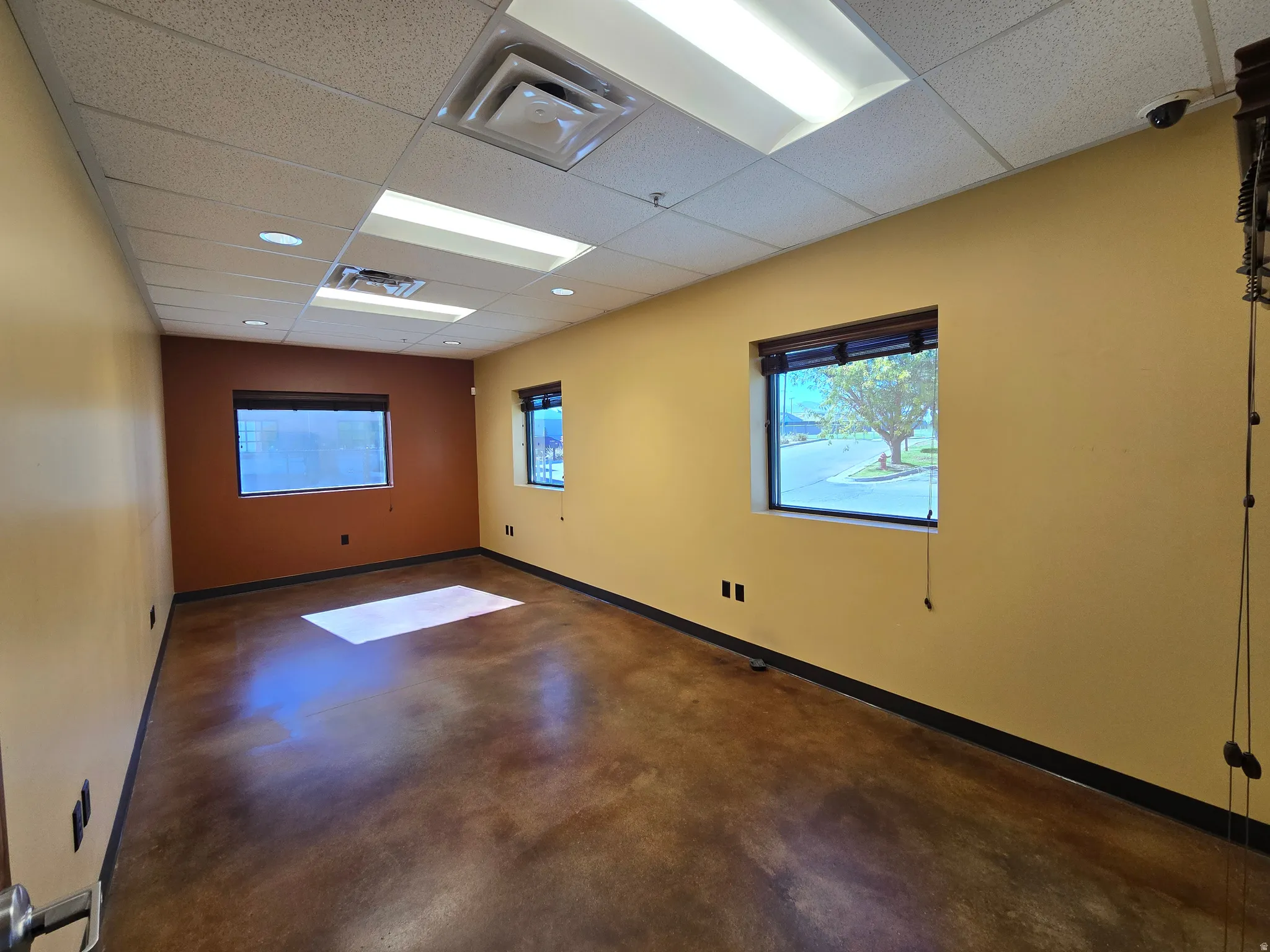 Empty room with a drop ceiling and concrete floors