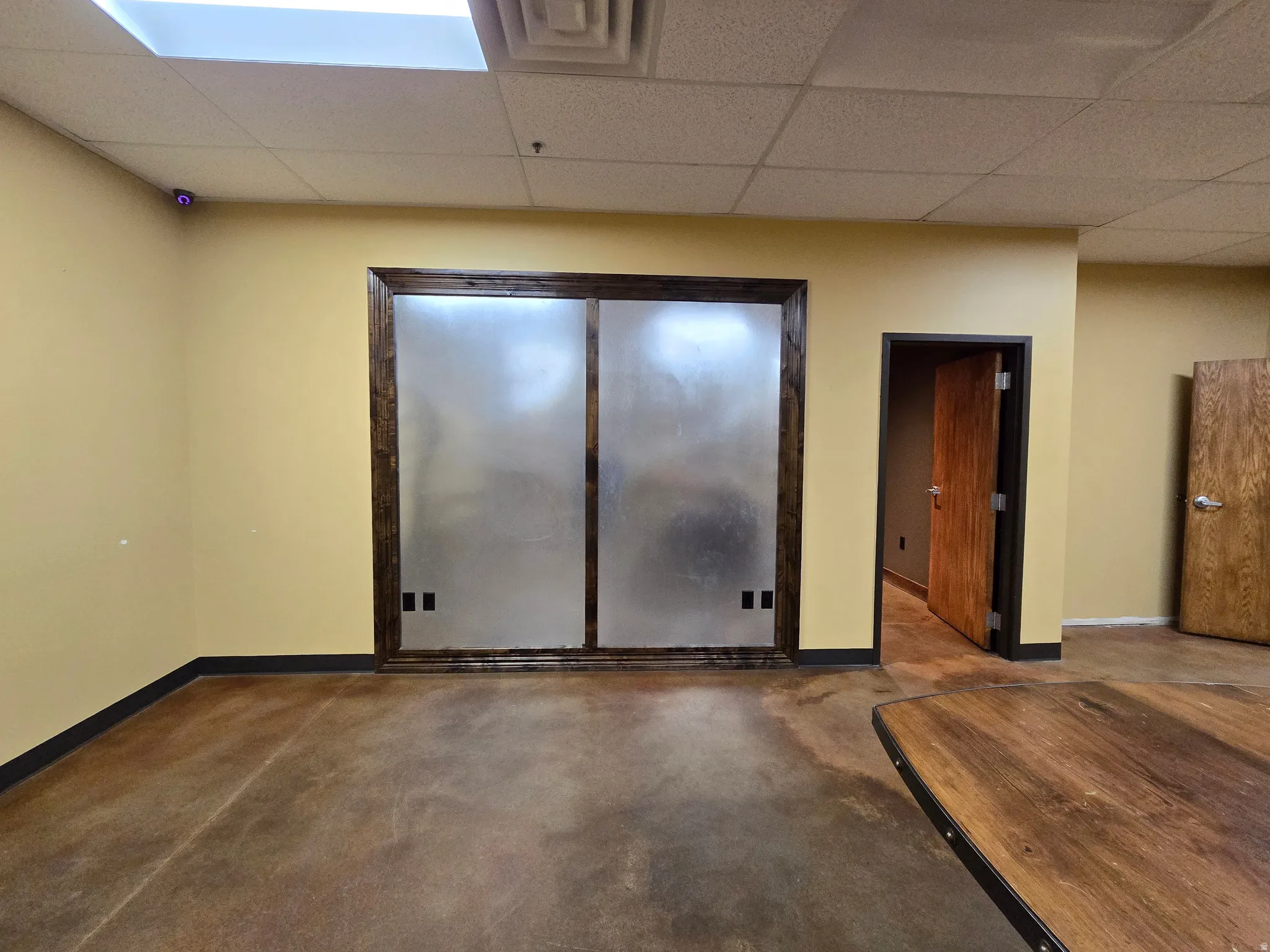 Empty room with a drop ceiling and concrete flooring