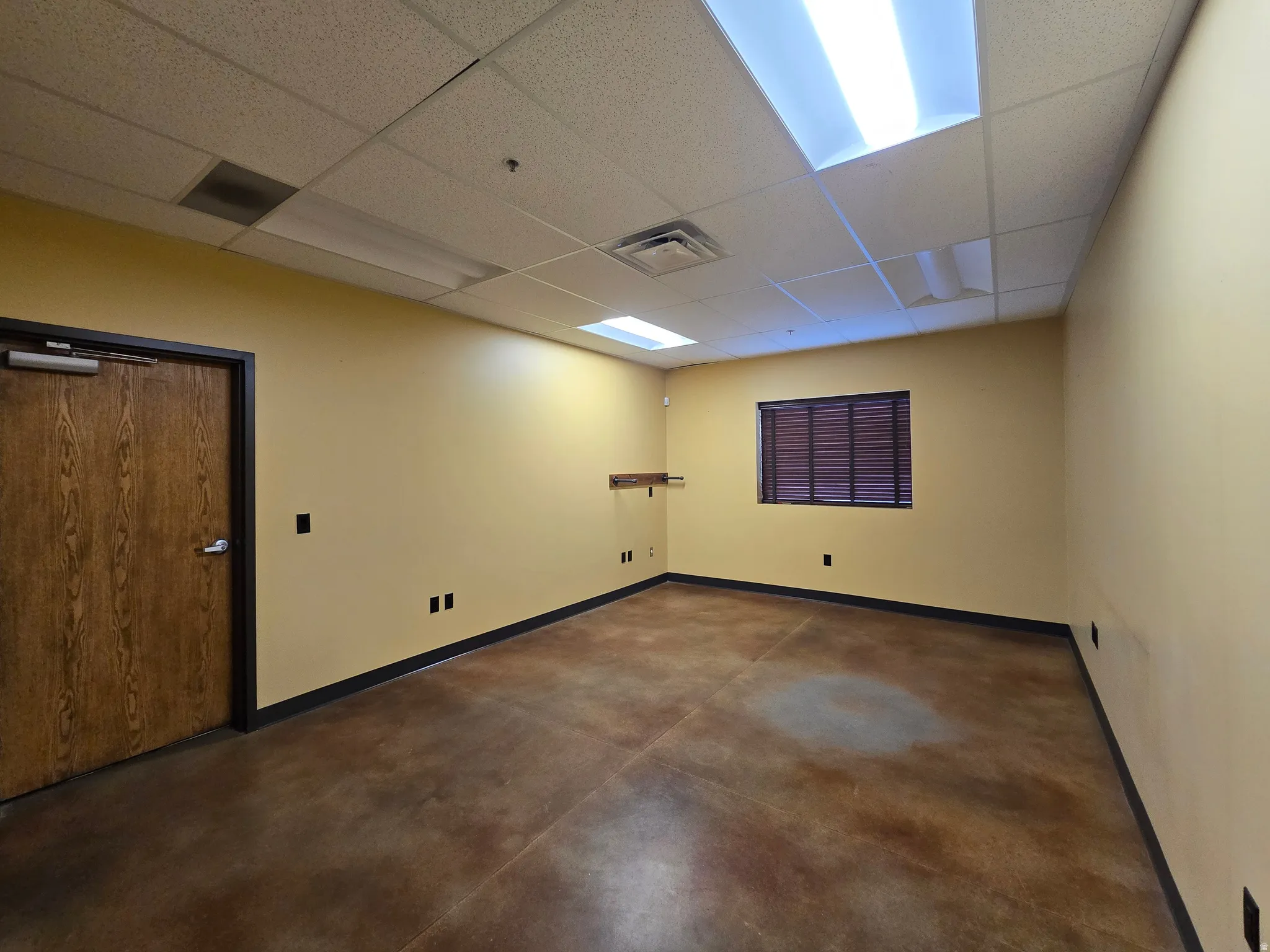 Spare room with finished concrete flooring and a paneled ceiling