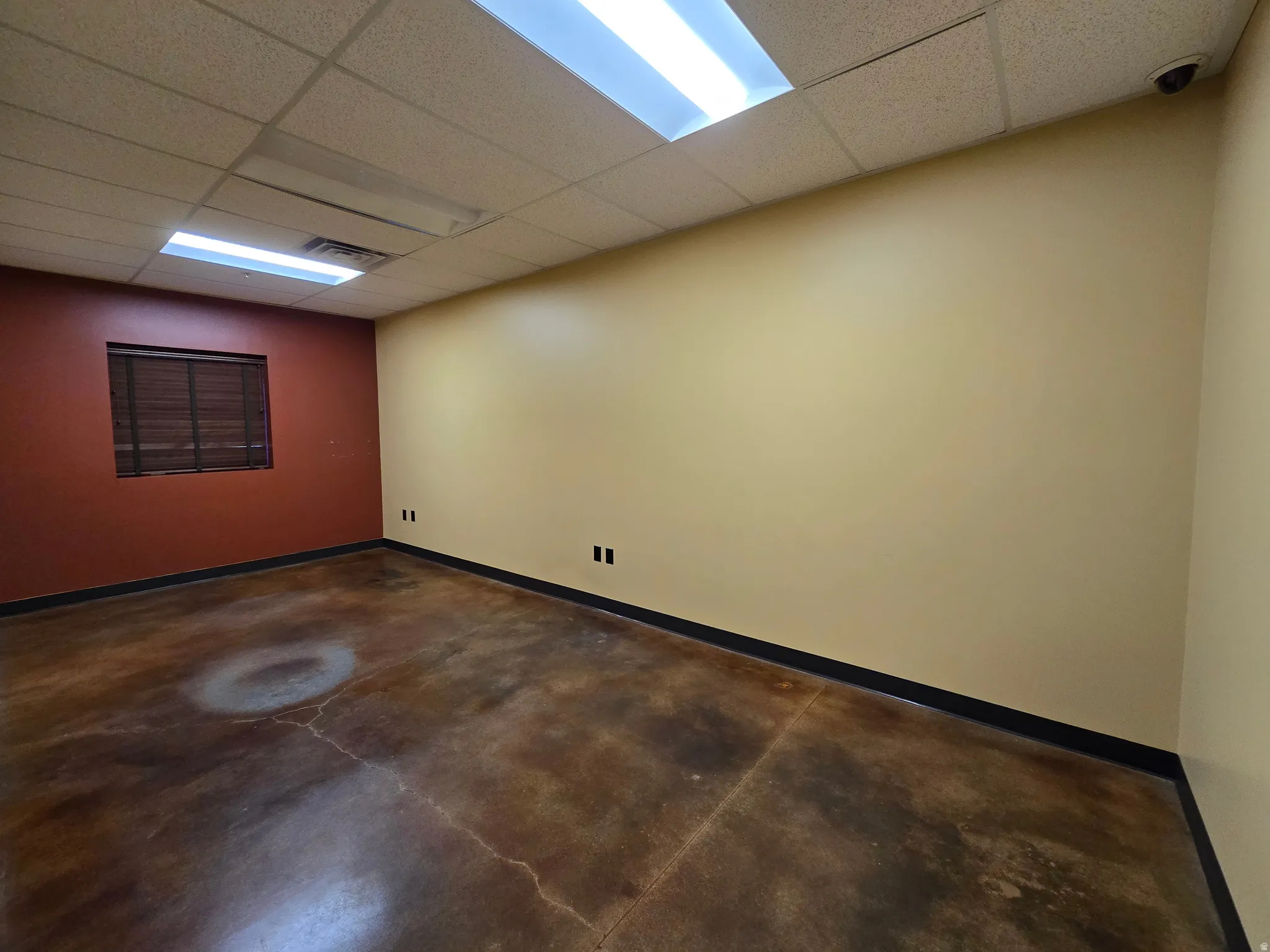 Empty room with a drop ceiling and concrete flooring