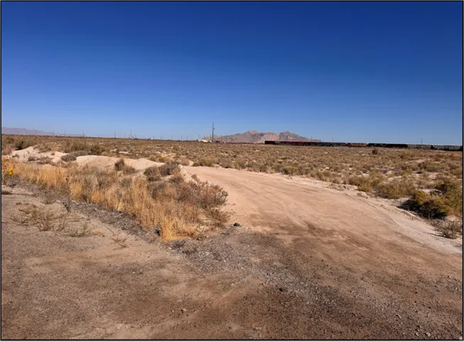 View of dirt / gravel road with a mountain view, a rural view, and view of desert