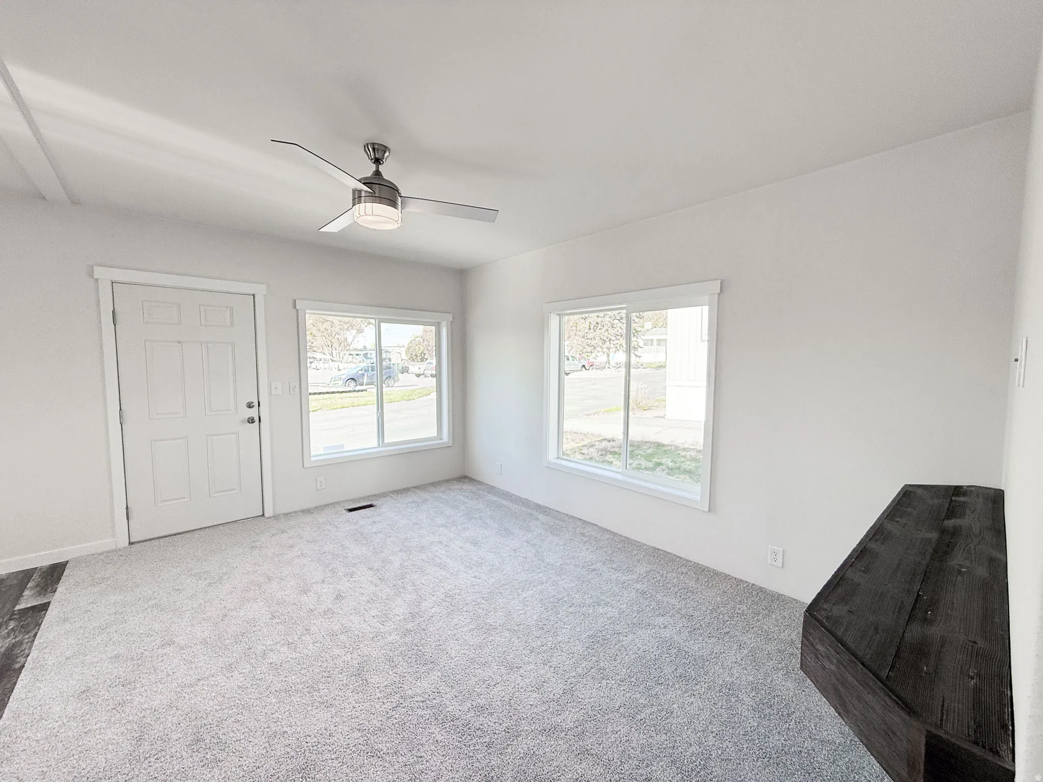 Unfurnished living room featuring carpet flooring and a ceiling fan