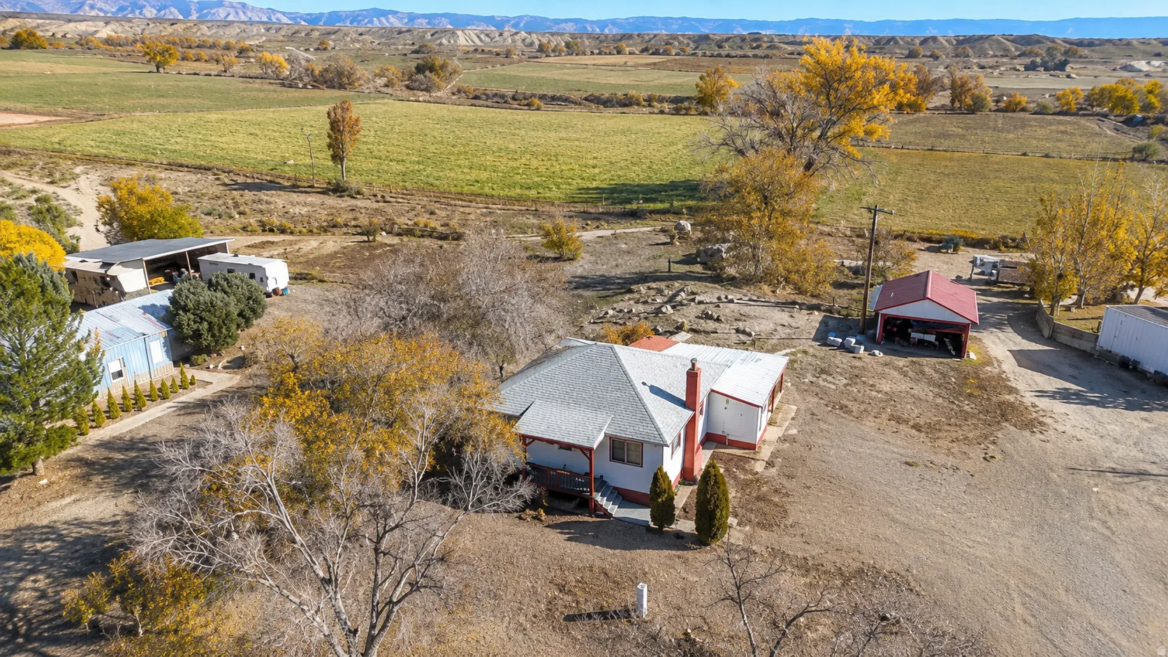 Ranch-style residence featuring a prominent red roof and chimney, situated on a substantial property with extensive unpaved areas