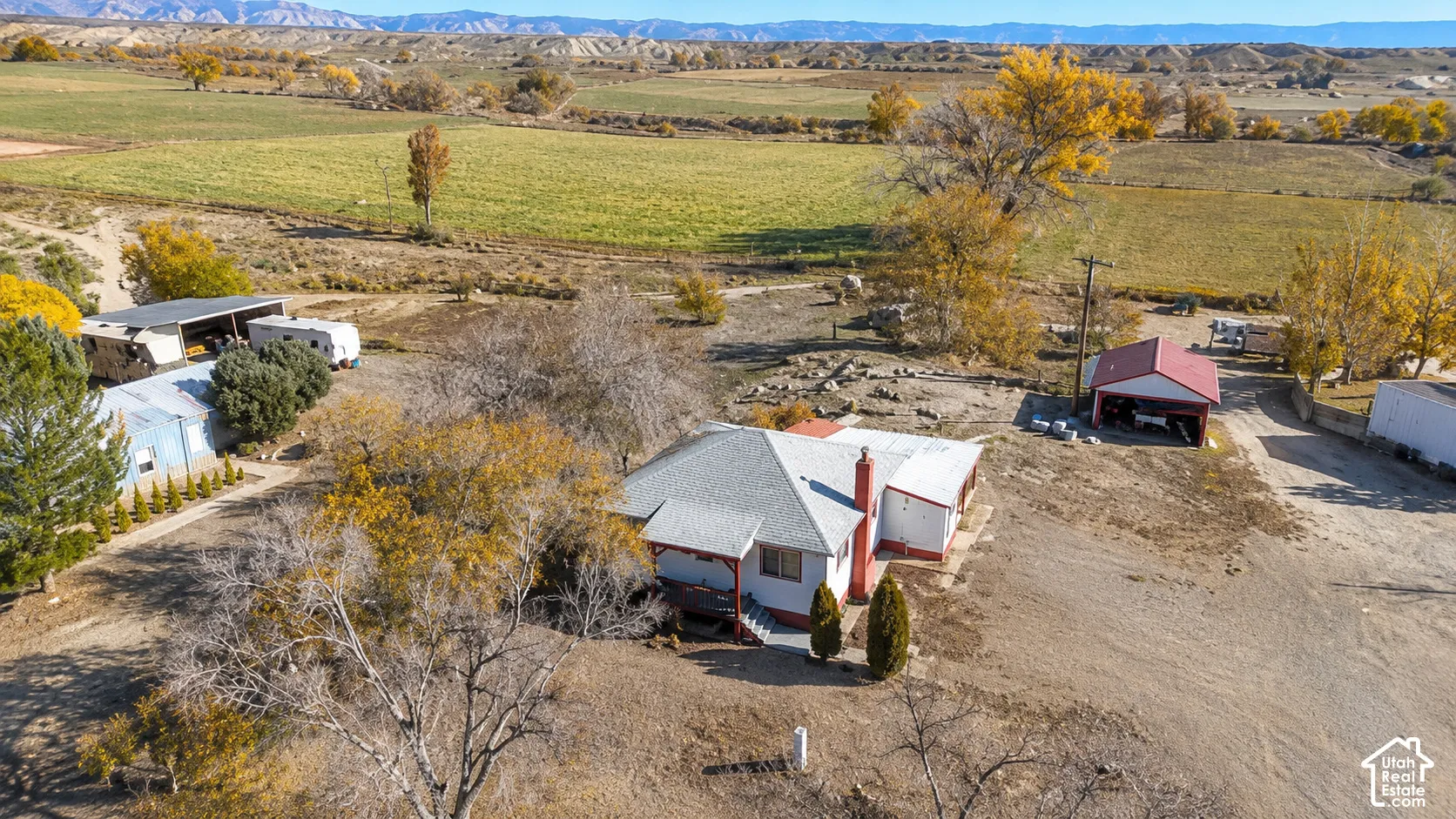 Ranch-style residence featuring a prominent red roof and chimney, situated on a substantial property with extensive unpaved areas