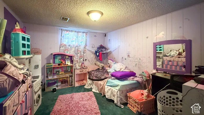 Bedroom with wood walls, a textured ceiling, and dark carpet