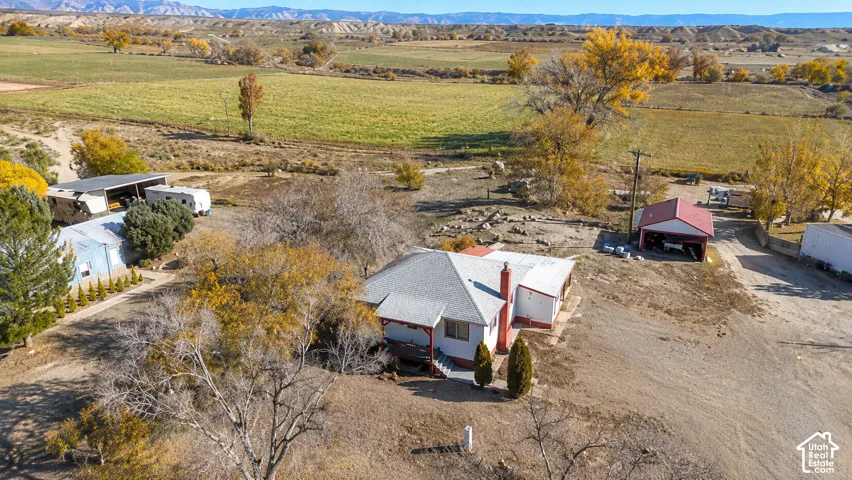 Ranch-style residence featuring a prominent red roof and chimney, situated on a substantial property with extensive unpaved areas