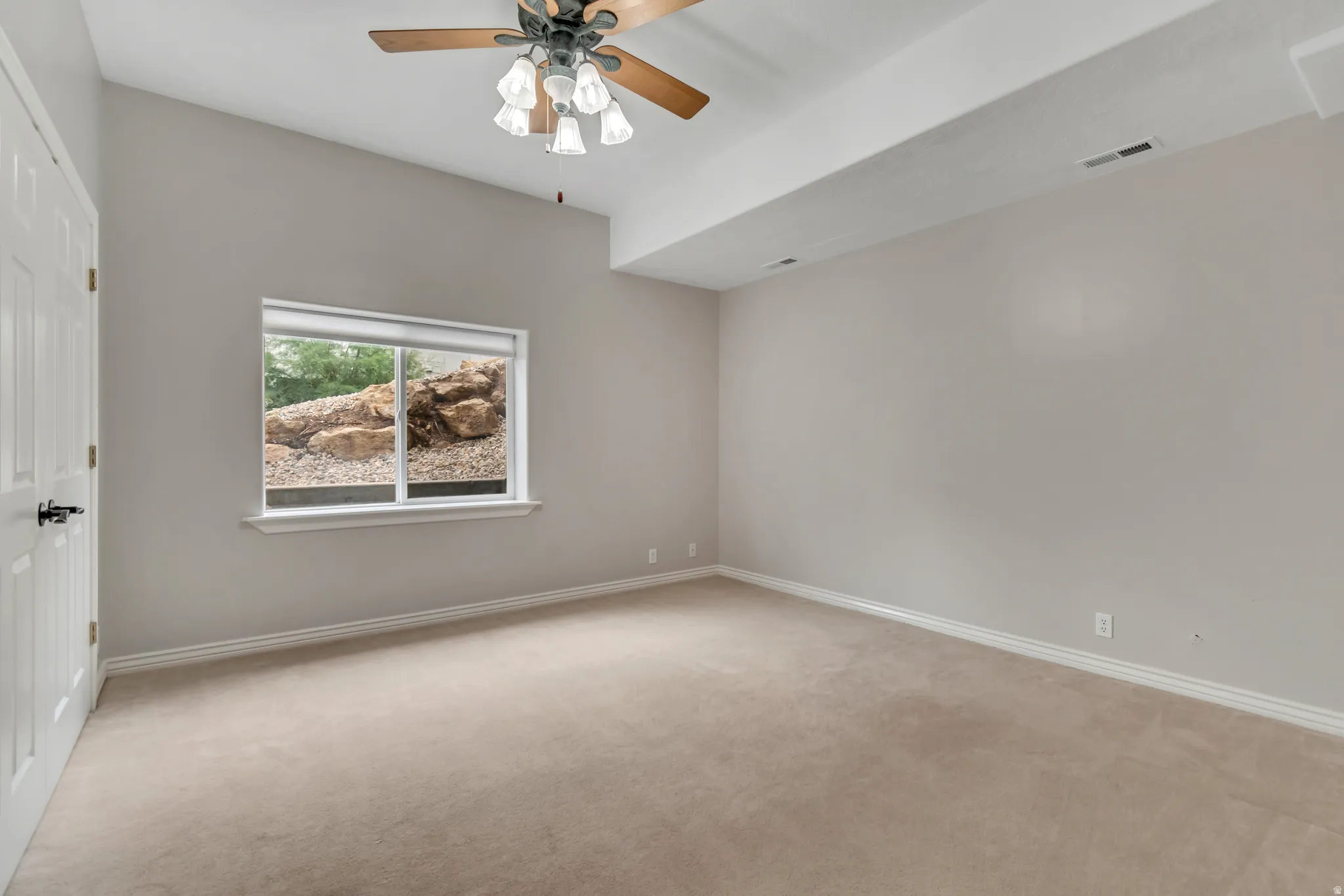 Spare room featuring light carpet and ceiling fan