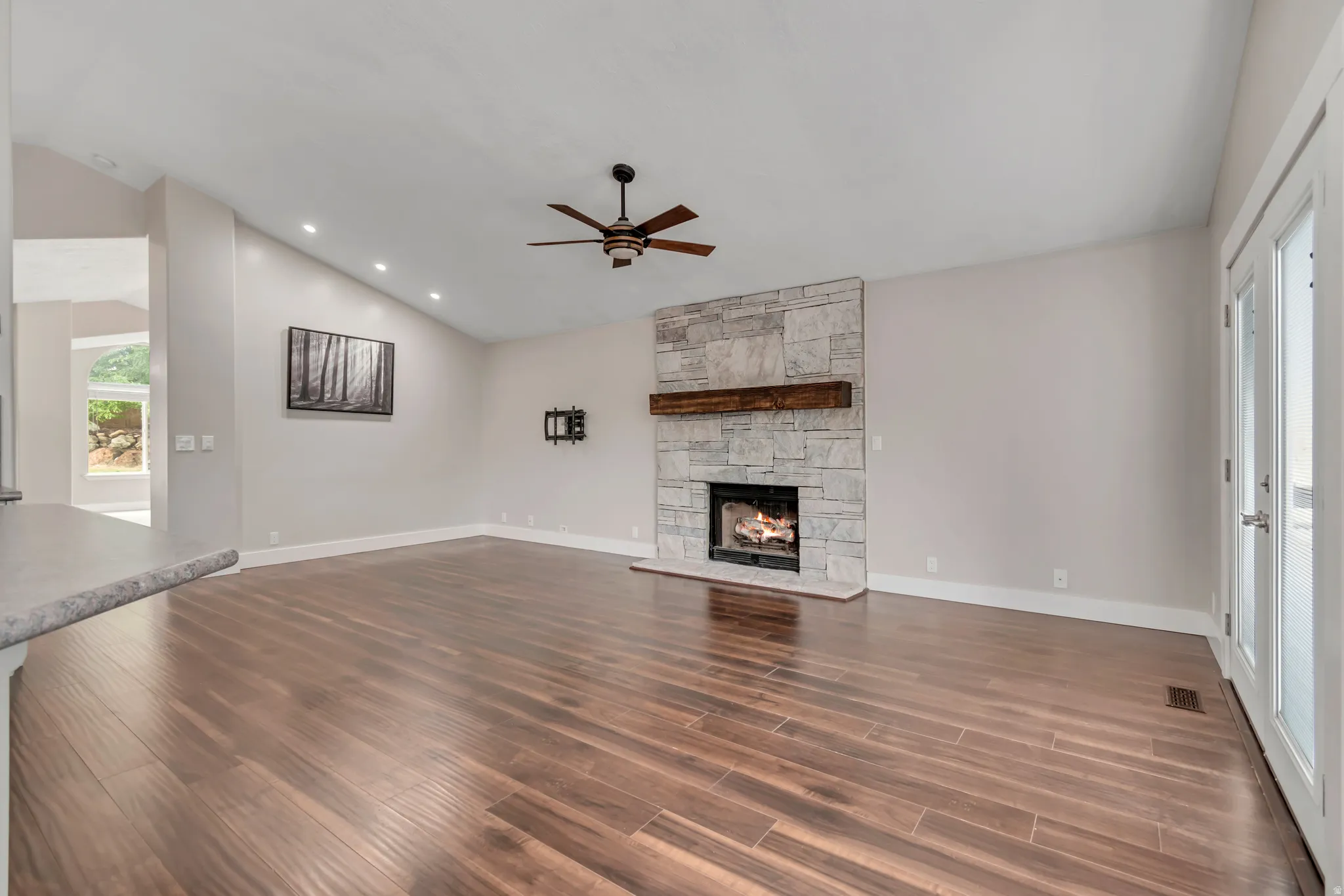 Unfurnished living room with lofted ceiling, a fireplace, dark wood-style floors, a ceiling fan, and recessed lighting
