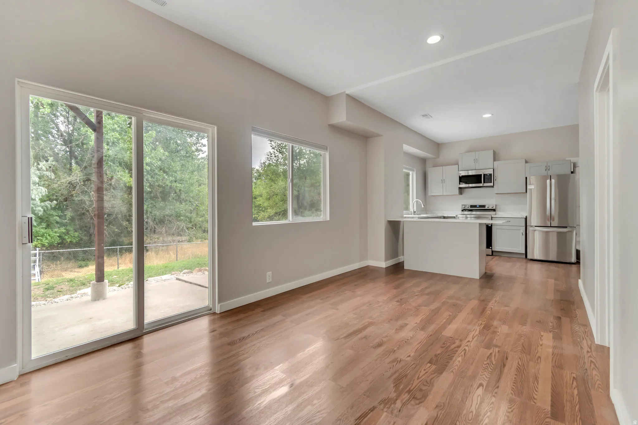 Kitchen featuring light countertops, a peninsula, appliances with stainless steel finishes, light wood finished floors, and open floor plan