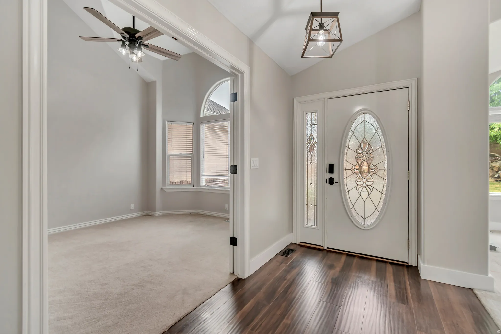 Foyer featuring lofted ceiling, dark wood-style floors, ceiling fan, and dark colored carpet