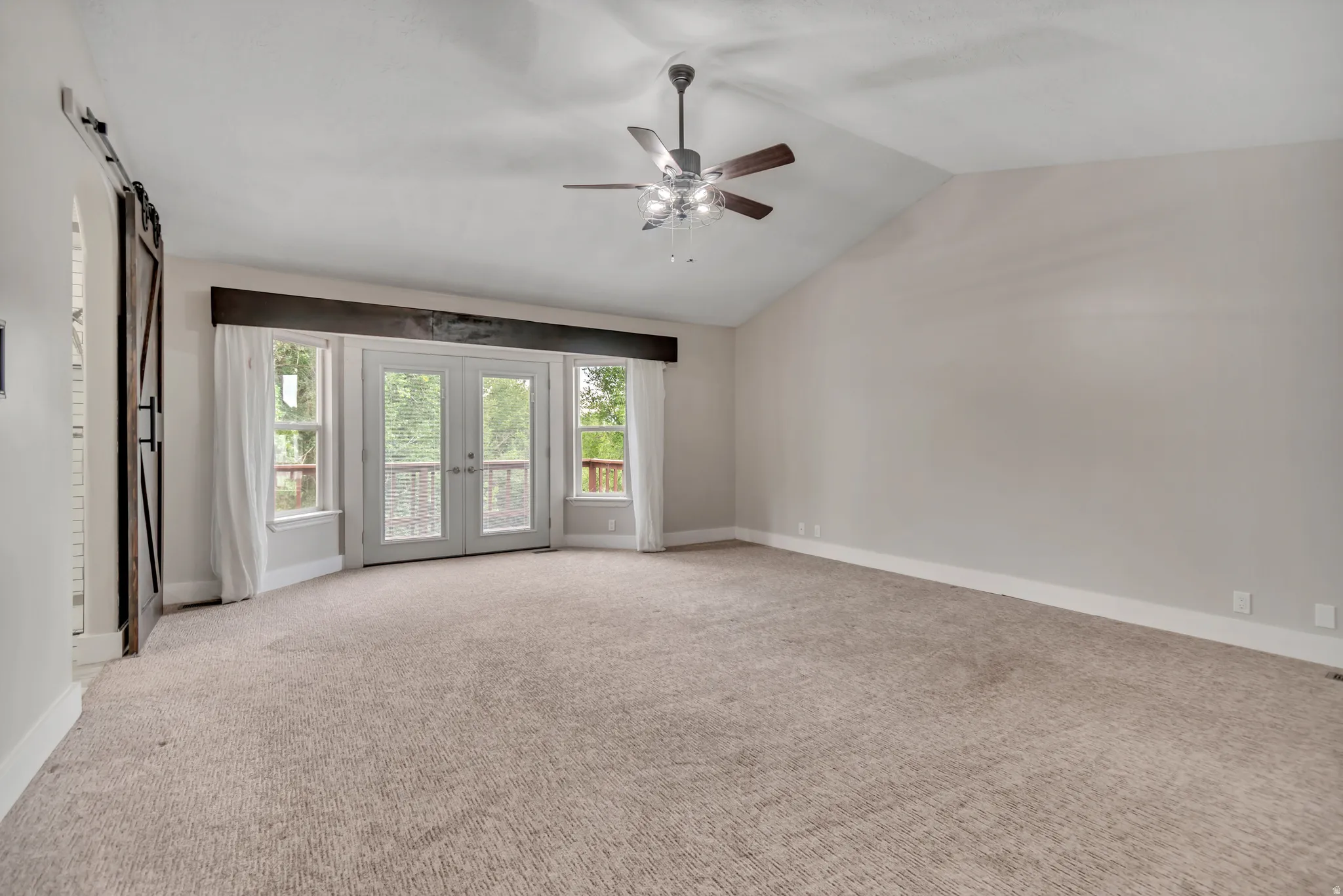 Unfurnished room with french doors, vaulted ceiling, light colored carpet, and ceiling fan
