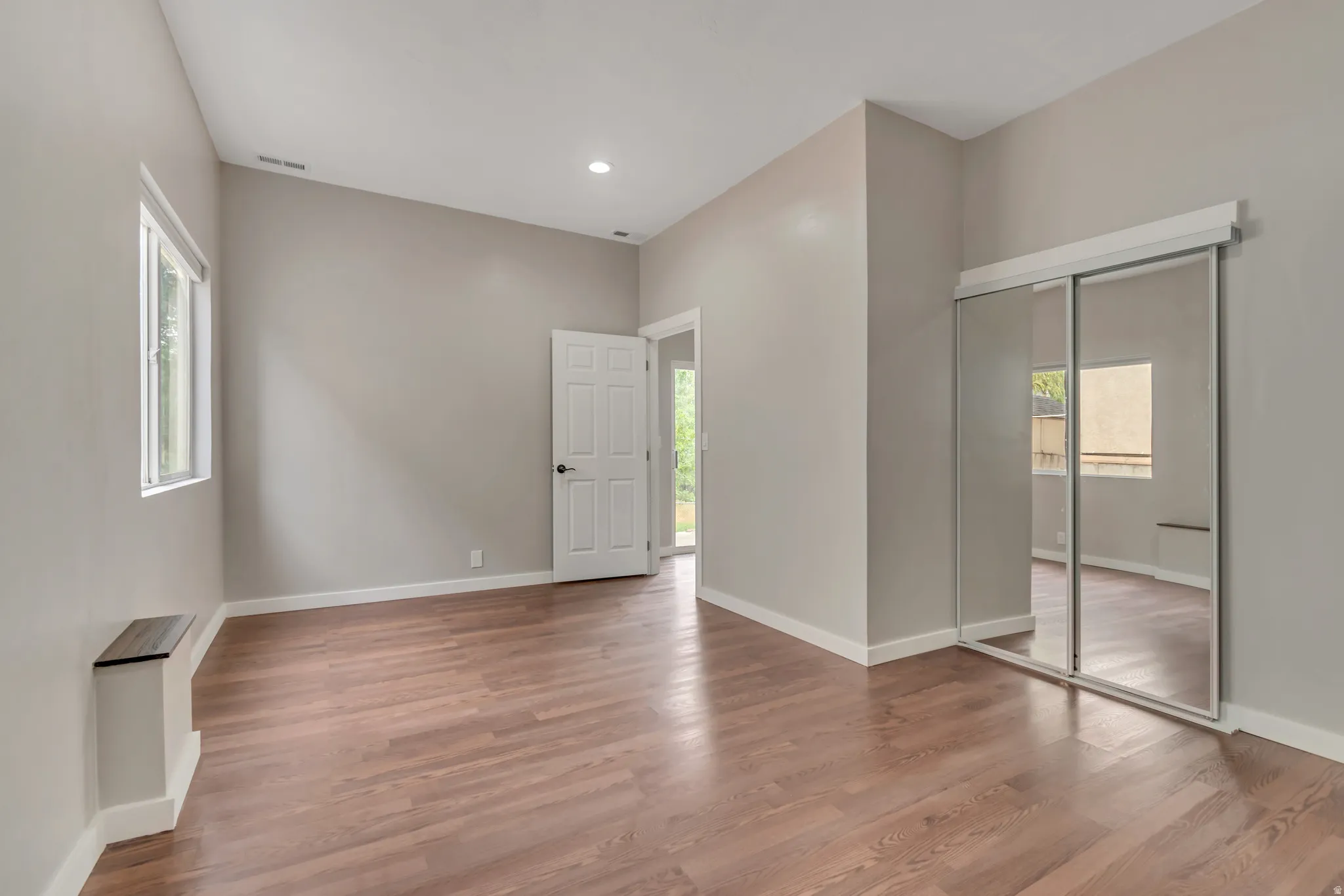 Unfurnished bedroom featuring multiple windows, wood finished floors, recessed lighting, and a closet