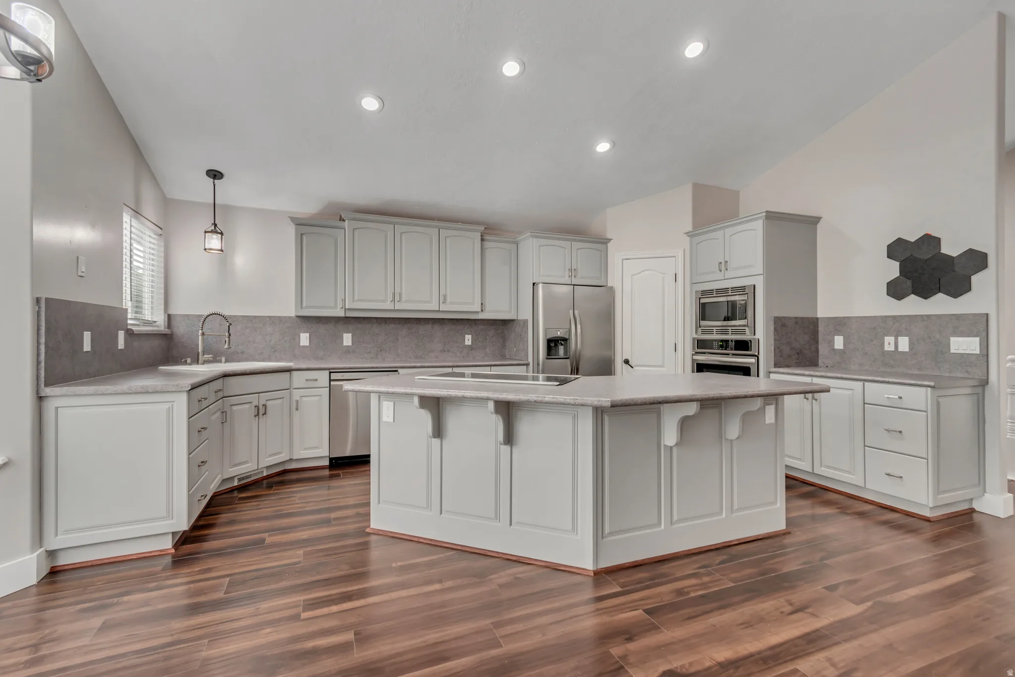 Kitchen with pendant lighting, decorative backsplash, appliances with stainless steel finishes, a kitchen bar, and recessed lighting