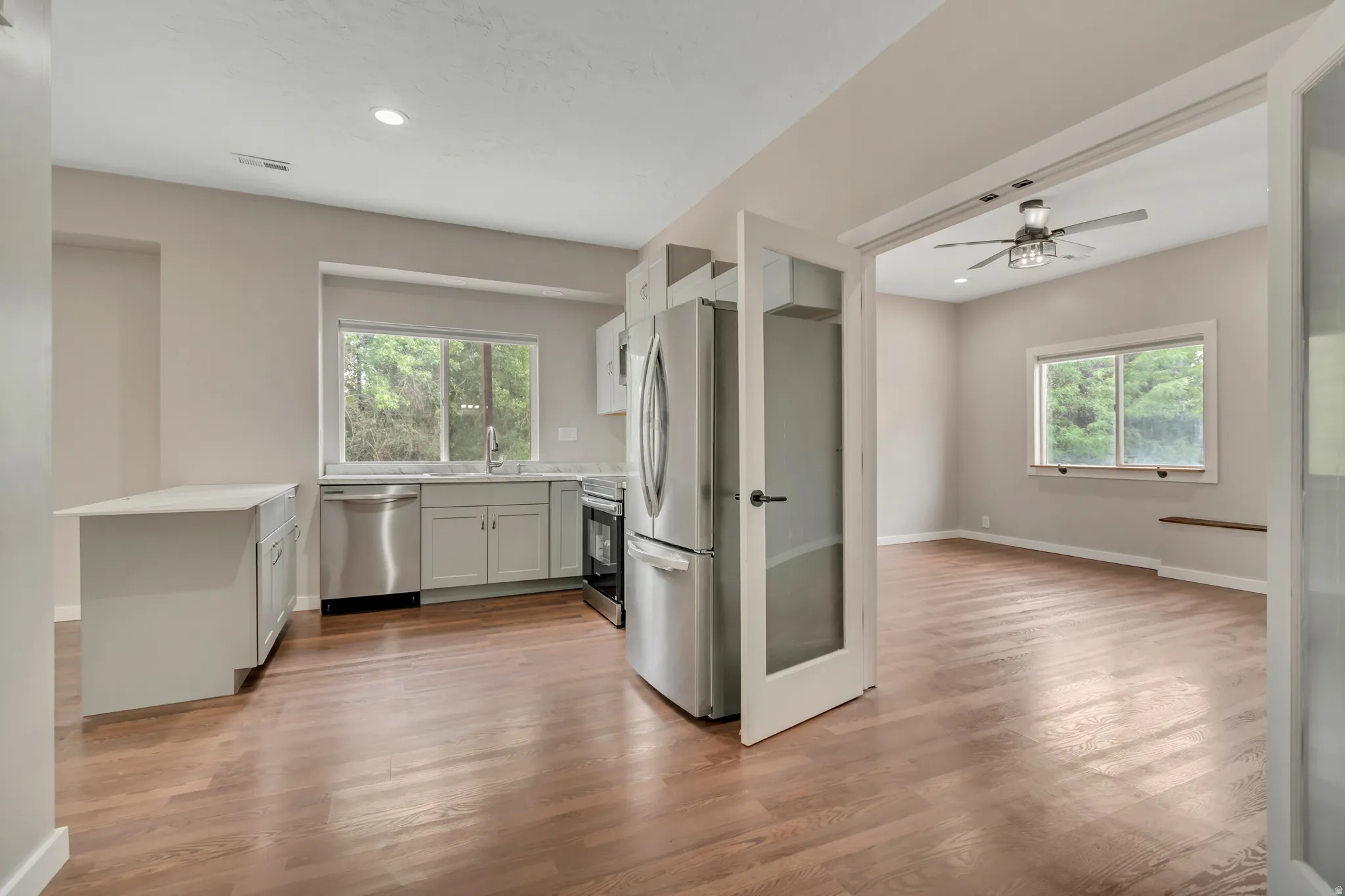 Kitchen featuring stainless steel appliances, light wood-style flooring, ceiling fan, recessed lighting, and light stone countertops