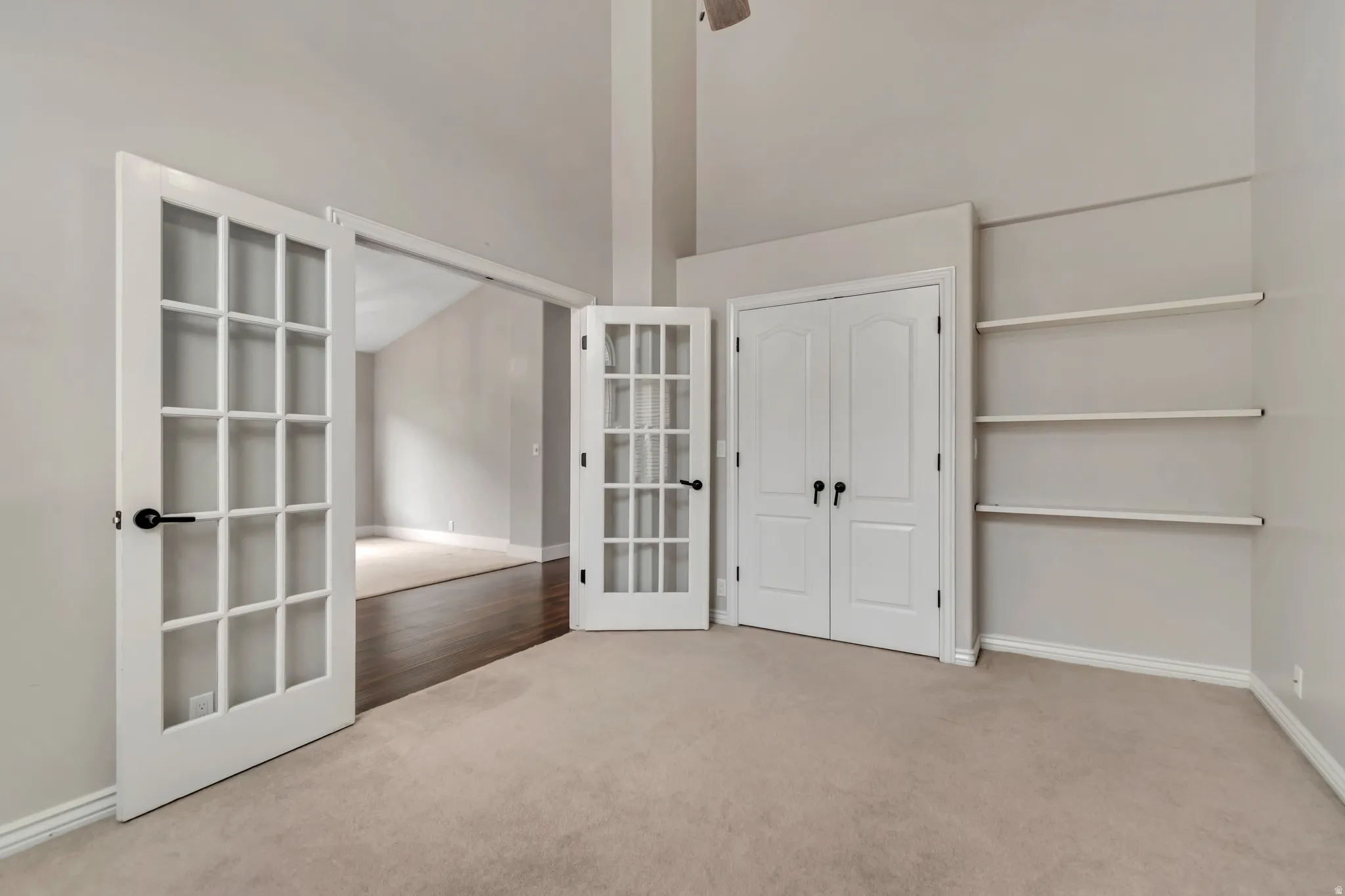 Unfurnished bedroom featuring french doors, light carpet, and a high ceiling