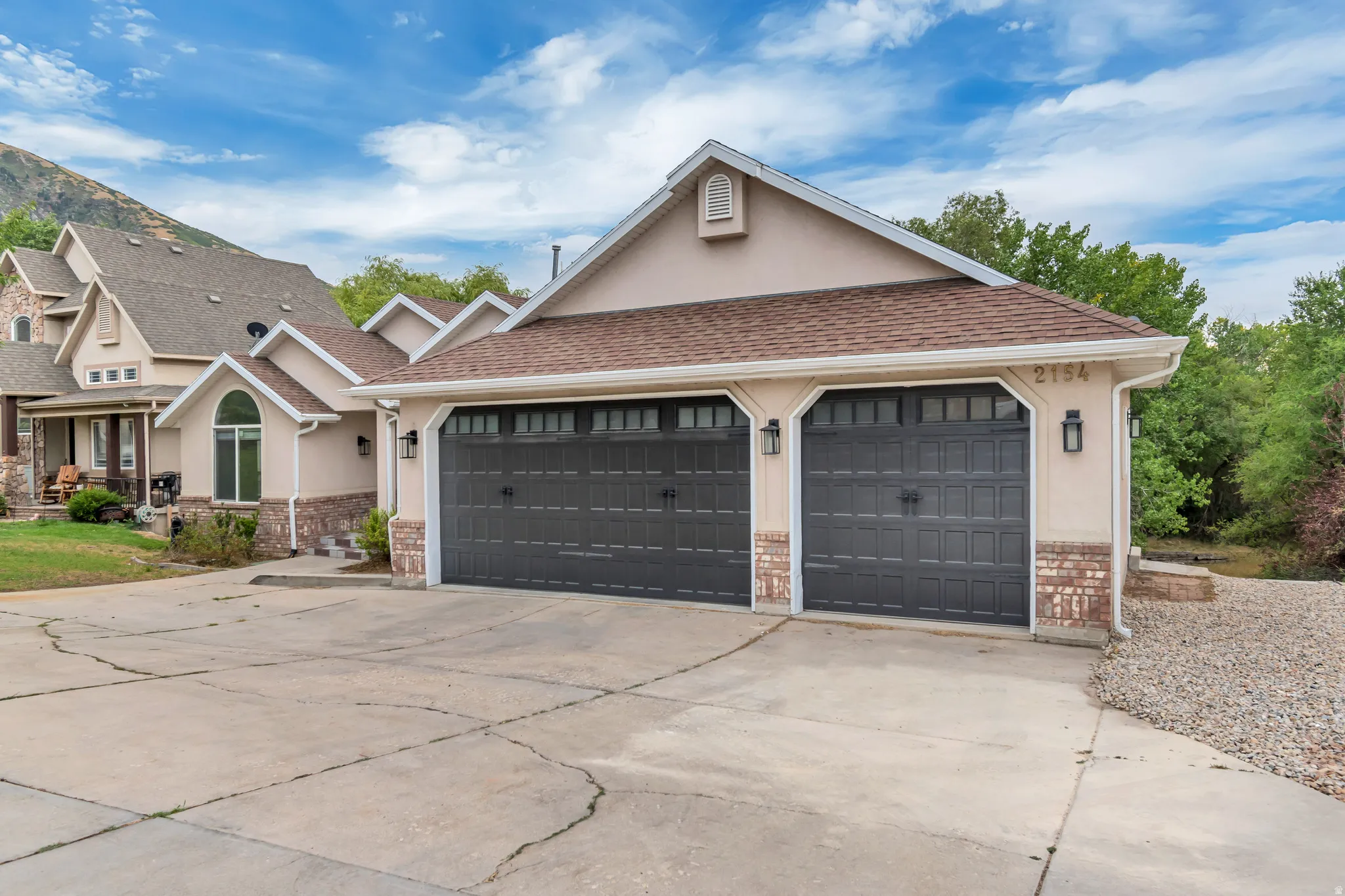 View of front facade with driveway, stucco siding, an attached garage, and roof with shingles
