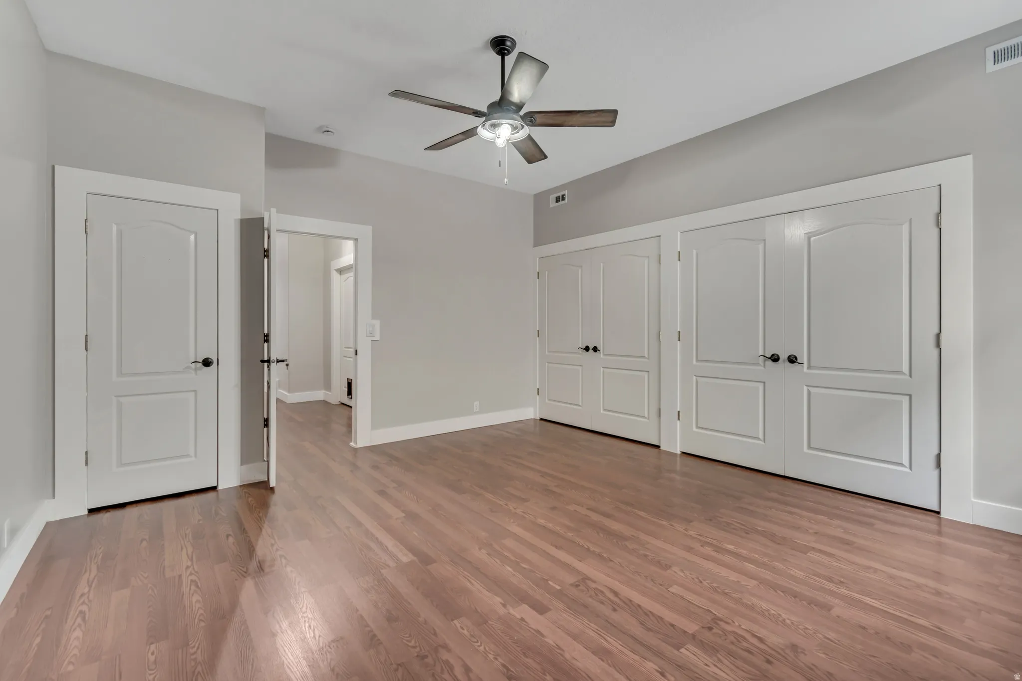 Unfurnished bedroom with multiple closets, light wood-type flooring, and ceiling fan