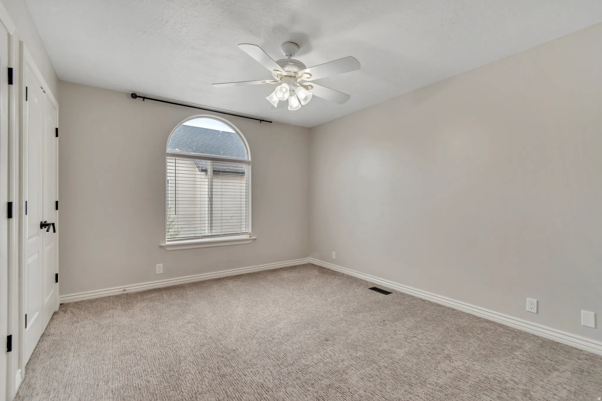Spare room featuring light colored carpet, ceiling fan, and a textured ceiling