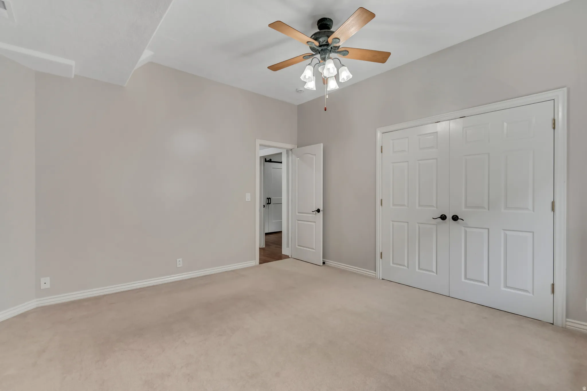 Unfurnished bedroom featuring light colored carpet, a ceiling fan, and a closet