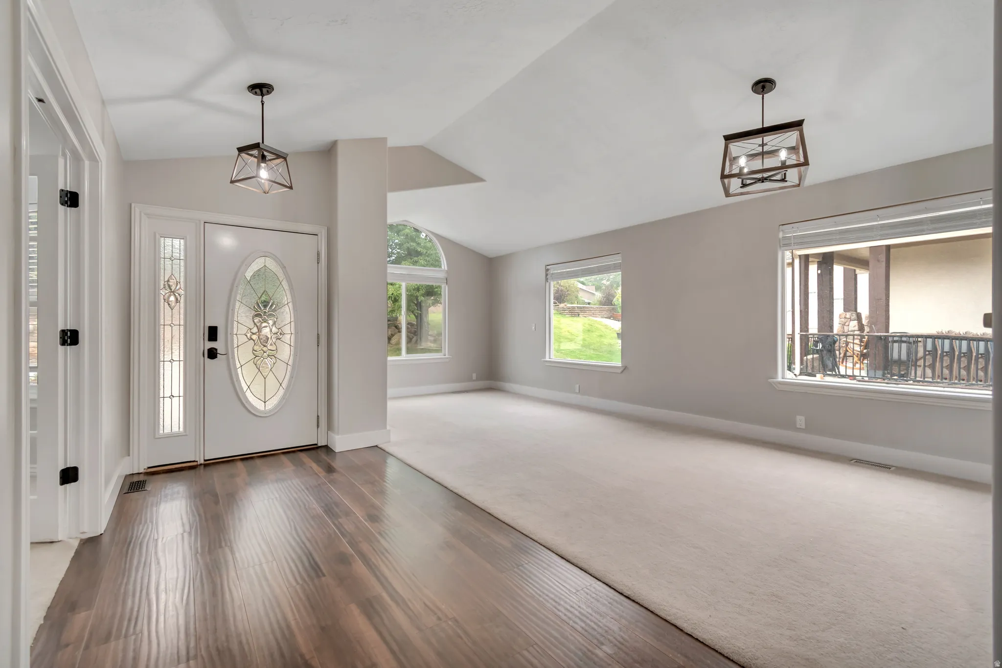 Entryway featuring healthy amount of natural light, vaulted ceiling, and wood finished floors