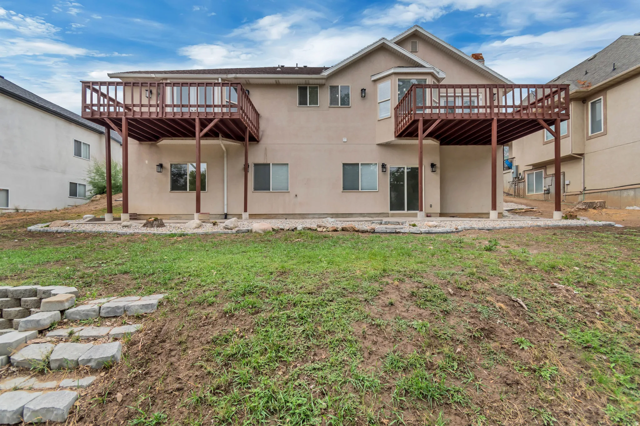 Rear view of property with a patio area, a deck, stucco siding, and a lawn