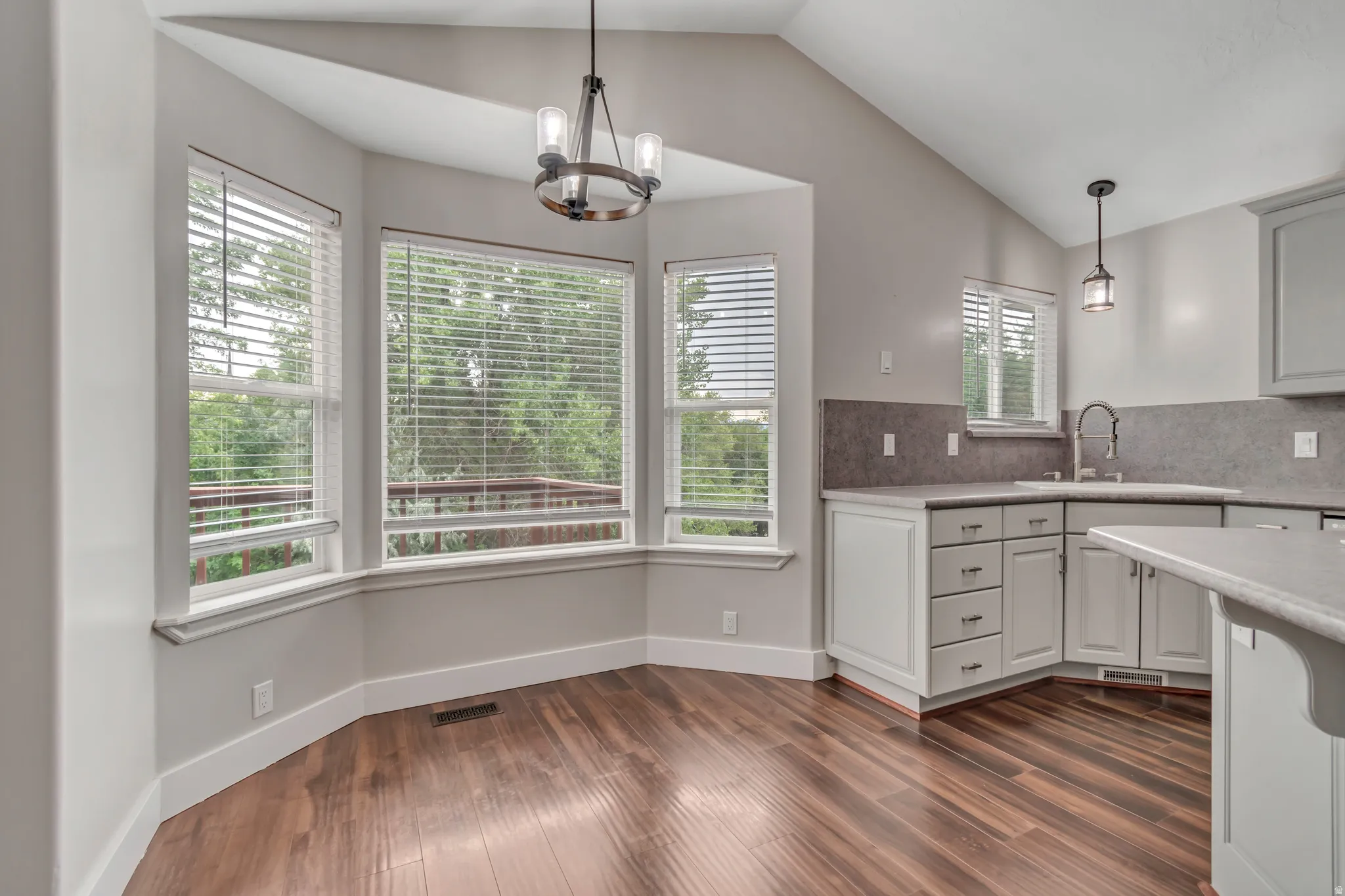 Kitchen featuring decorative light fixtures, lofted ceiling, dark wood-style flooring, a chandelier, and decorative backsplash