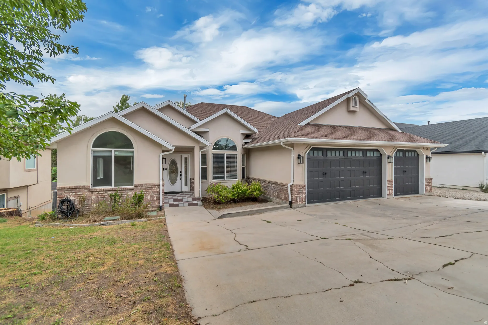 Ranch-style home featuring stucco siding, concrete driveway, a garage, brick siding, and a front yard