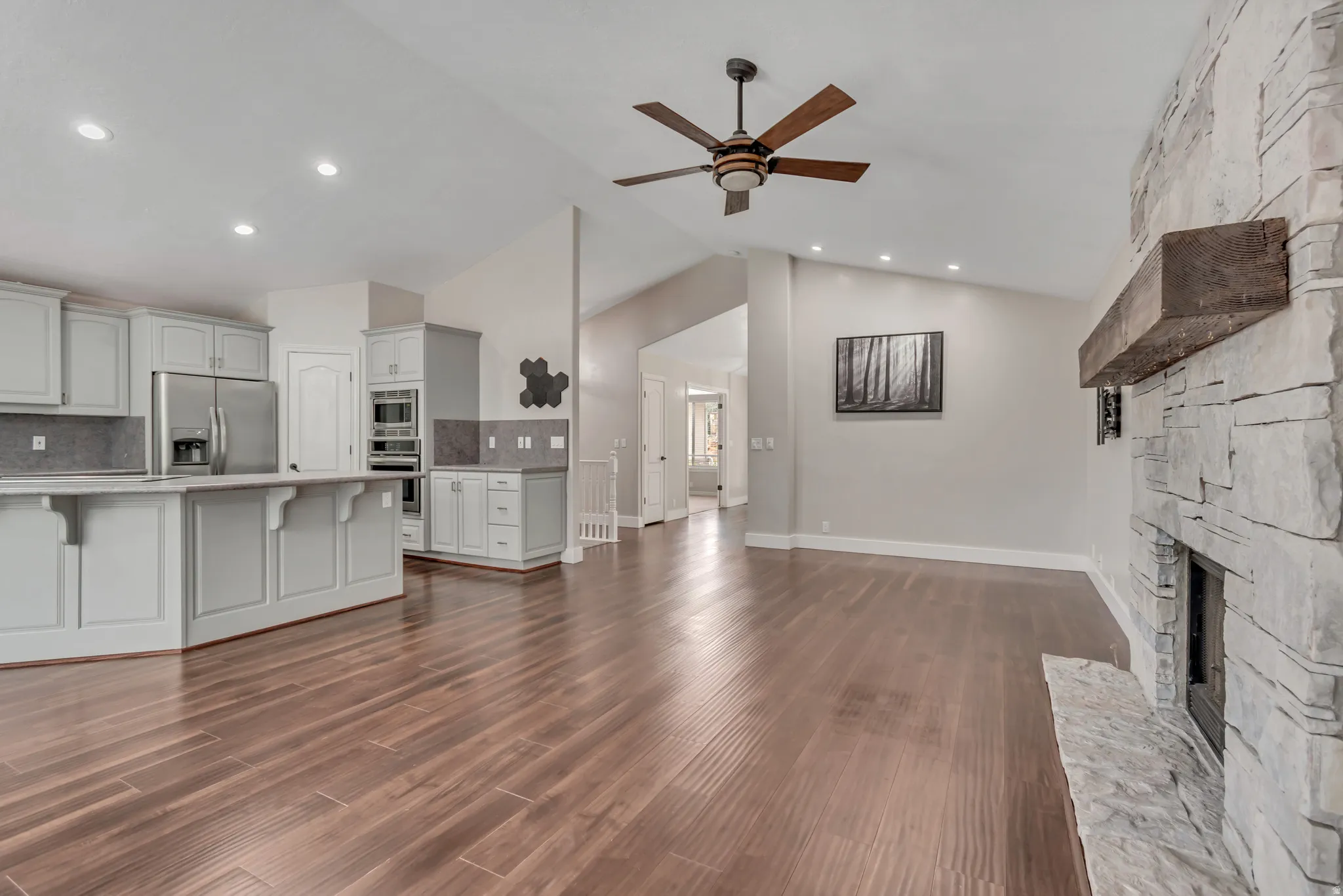 Unfurnished living room featuring vaulted ceiling, a ceiling fan, a fireplace, dark wood finished floors, and recessed lighting