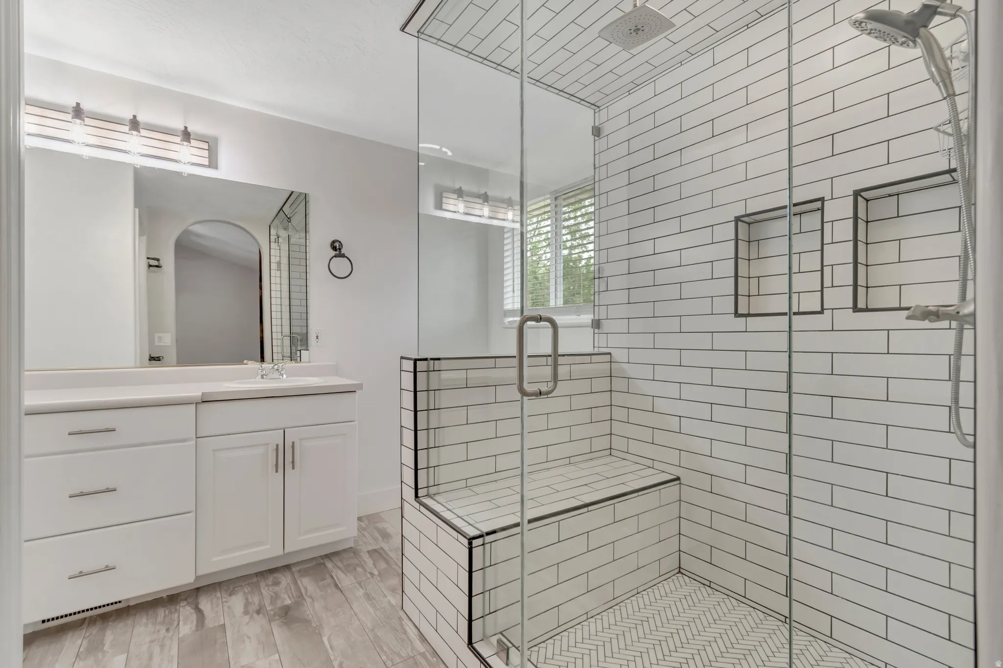 Bathroom featuring vanity, a stall shower, and light wood-type flooring
