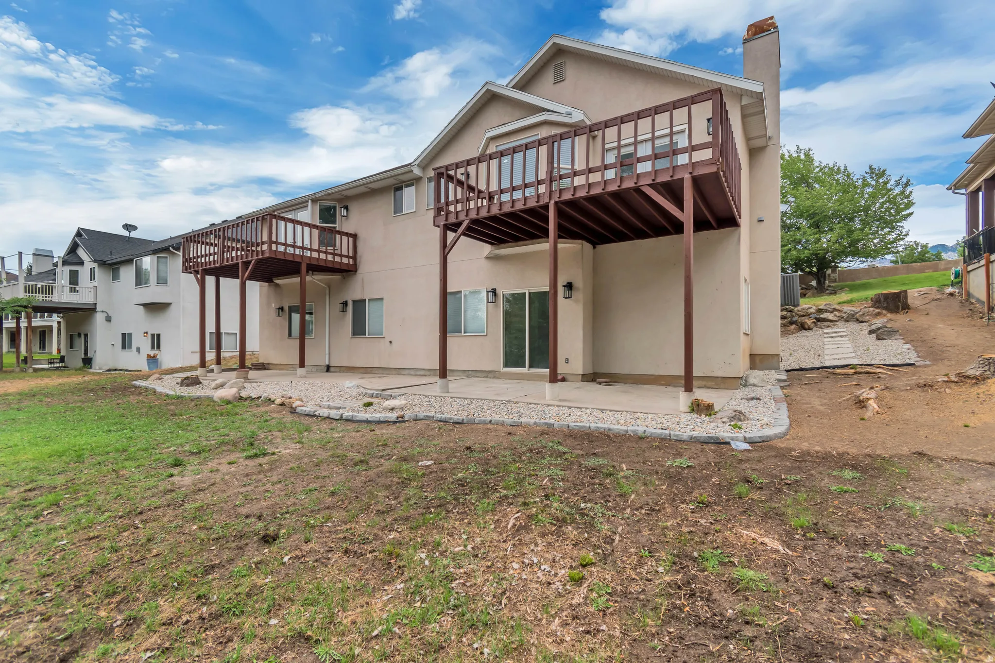 Rear view of property featuring a patio, a chimney, a wooden deck, and stucco siding