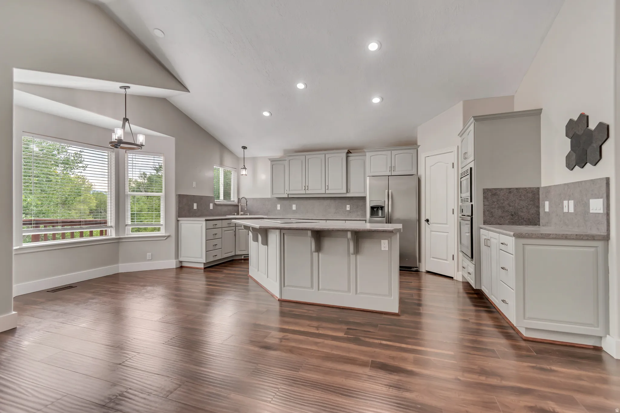 Kitchen with a kitchen island, a breakfast bar, hanging light fixtures, stainless steel appliances, and backsplash