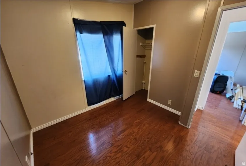 Unfurnished bedroom with dark wood-type flooring and baseboards