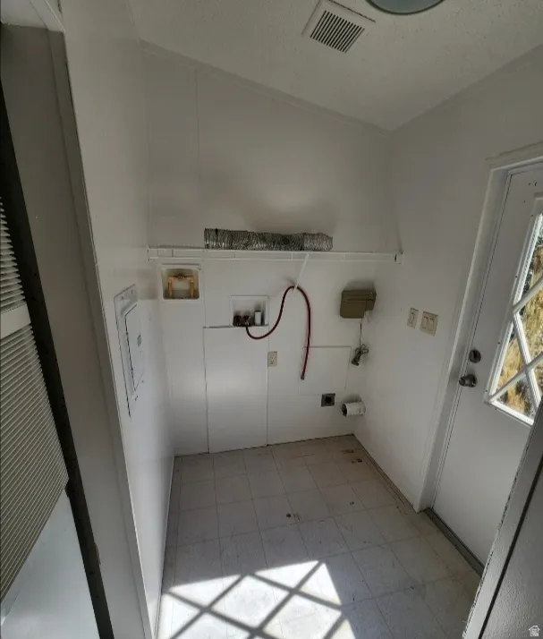Laundry room featuring hookup for a washing machine, light floors, and a heating unit