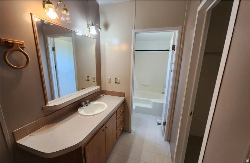 Bathroom with vanity, shower / bath combination, and light flooring