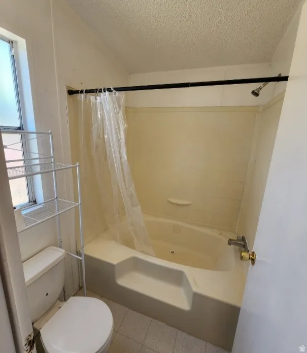 Full bathroom with a textured ceiling, shower / bath combination with curtain, and light tile patterned flooring