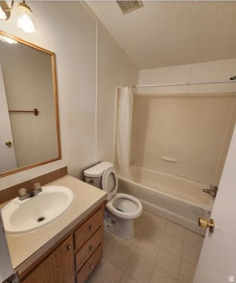 Full bath featuring shower / bath combination with curtain, a textured ceiling, and vanity