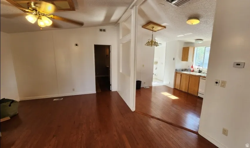 Unfurnished living room featuring dark wood finished floors, a textured ceiling, and a ceiling fan