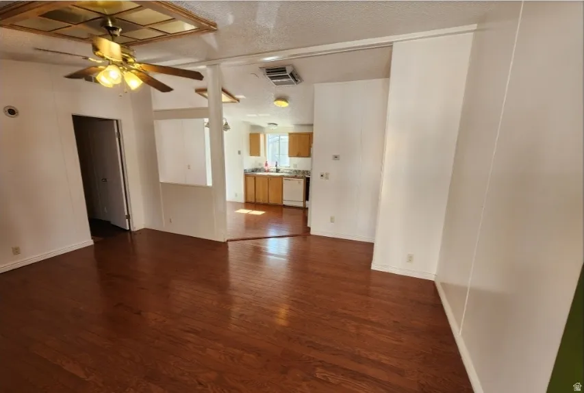 Unfurnished living room with dark wood finished floors, ceiling fan, and a textured ceiling